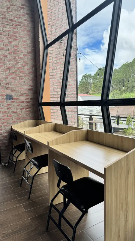 Bàn gỗ cạnh cửa kính nhìn ra đồi thông